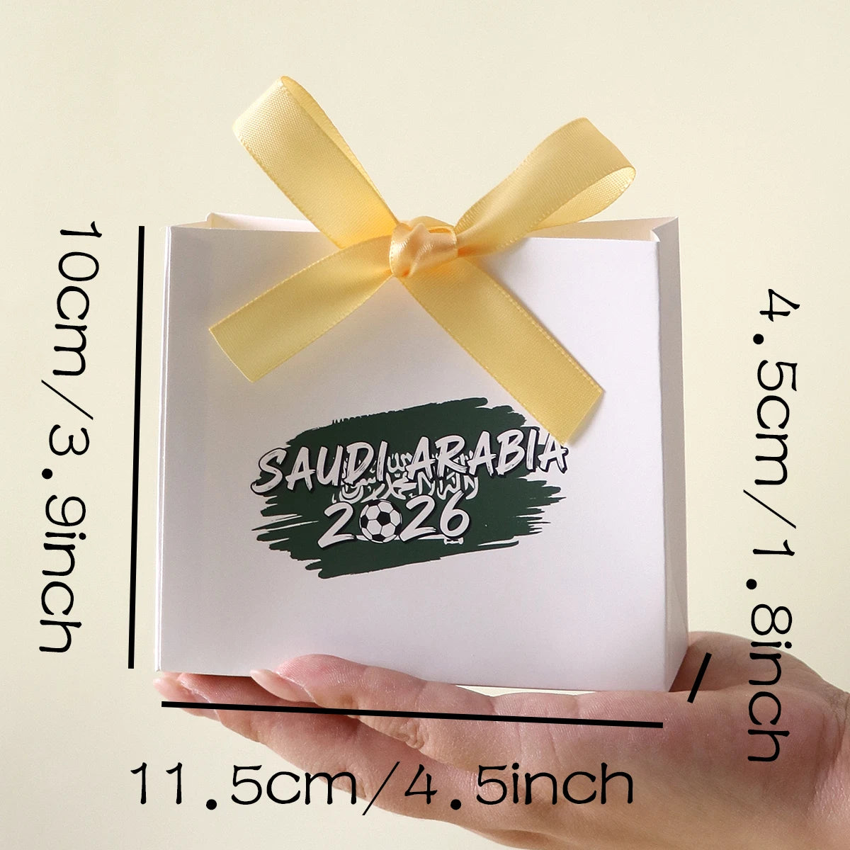 Saudi Arabia 2026 Football-Themed Gift Box, Simple White Box with Green Football Print, Adorned with a Delicate Yellow Satin Ribbon Bow, Featuring a Clean and Elegant Design The Box Has Clear Printing and a Fine Texture, Maki Qme
