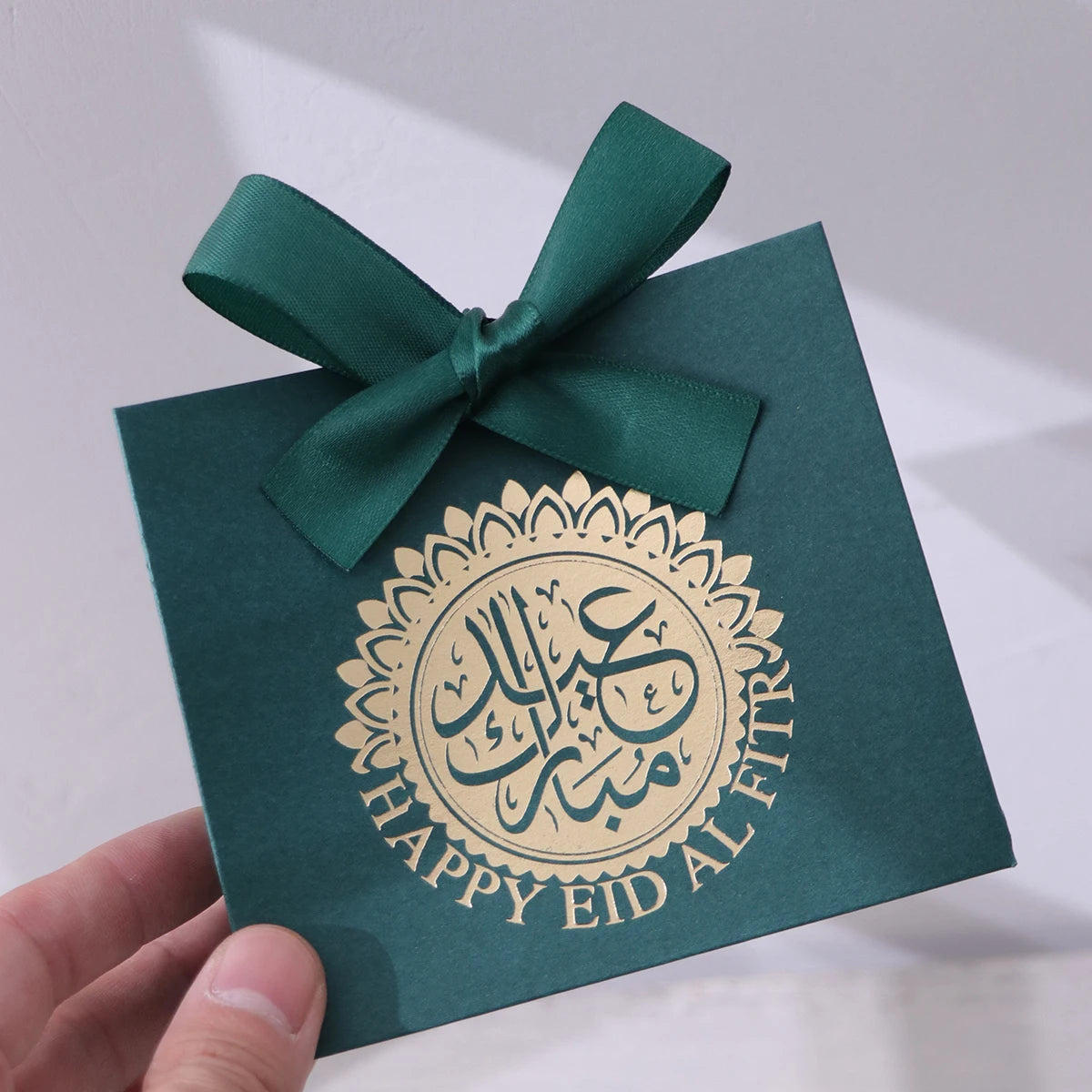 5 Exquisite and Compact Eid Gift Boxes, Each Featuring Elegant Black, Luxurious Green, and Pure White as Their Main Colors, Adorned with Delicate Arabic Script and Golden Circles, and Tied with Luxurious Gold and Silver Ribbo Qme