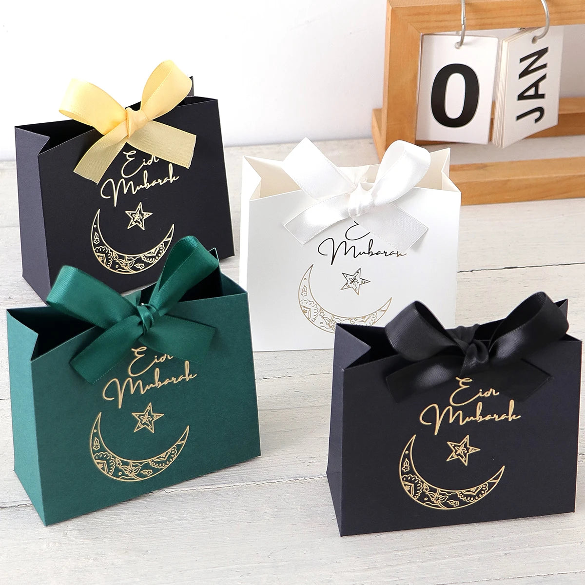5 Exquisite and Compact Eid Gift Boxes, Available in Elegant Black, Luxurious Green, and Pure White, Decorated with Delicate Gold and Silver Star and Moon Patterns, and Adorned with Luxurious Gold and Silver Ribbons. These Gi Qme